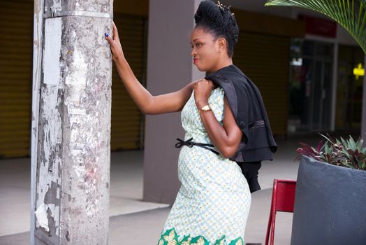 happy business woman relaxes against a wall after work on the street