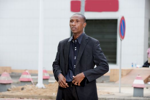 professional businessman standing in town and adjusting his suit outdoors