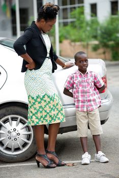 young businesswoman standing near a car and talking with her son