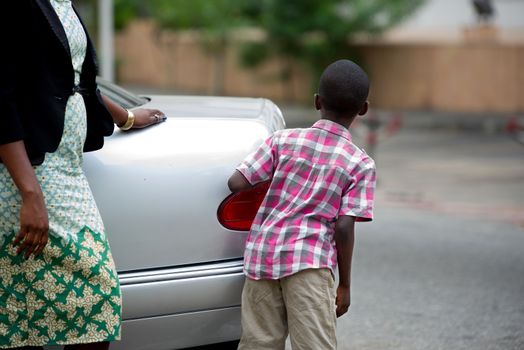child standing back from a car and looking away