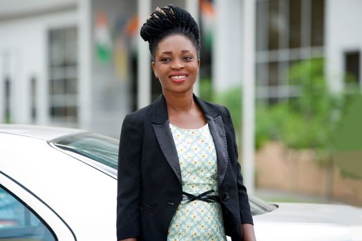 Confident and smiling businesswoman in black suit standing outdoors (day)