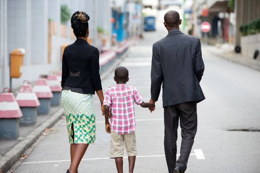 happy family holding their child walking together in city
