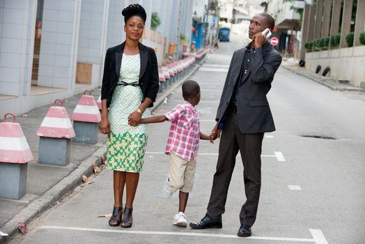 young happy couple holding their son, having fun walking together in the city