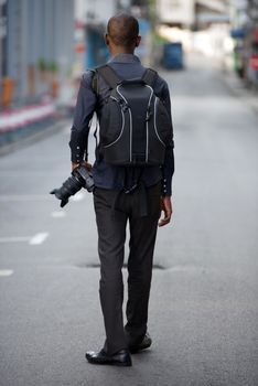 Young man tourist exploring alone while walking with a camera and a backpack and observes the place to take pictures.