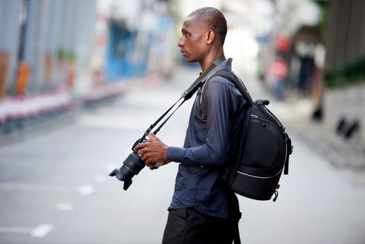 Young student explores new city and culture  while walking around tourist attractions with analog camera and a backpack.