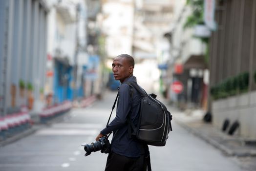 young tourist walking in the city with a camera and a backpack,