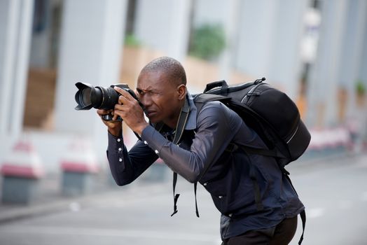 Young man photographer takes a picture of the city and its buildings. Concept of travel and tourism.