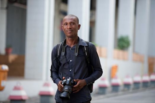 Portrait of smiling young tourist with camera in hand discovering the city and taking pictures