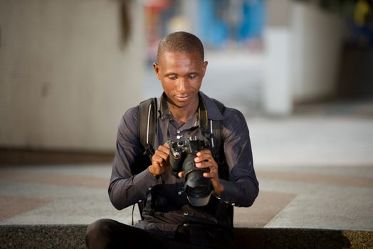 young smiling tourist sitting on stairs looking at his pictures taken during the walk in the camera