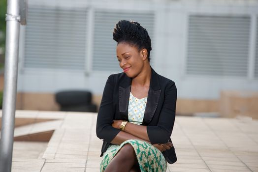 portrait of smiling woman with closed eyes sitting alone on steps in front of a building