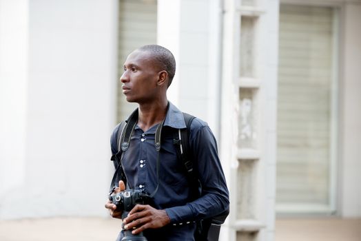 Young tourist walking with a camera at the neck in the city looking for a pretty place to photograph