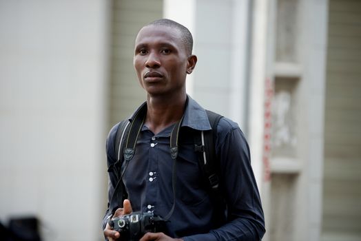 Young tourist walking with a camera at the neck in the city looking for a pretty place to photograph