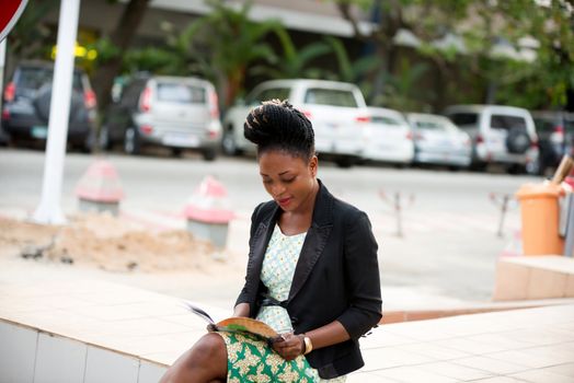 Confident smart woman reading business book looking at camera. Serious beautiful businesswoman interested in self-education. Student concept