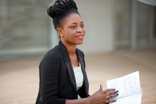 smiling businesswoman sitting outdoors and reading a book