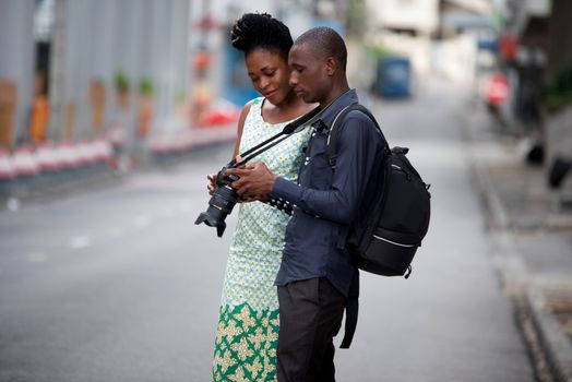 tourist couple walking in the city and together looking at the pictures in the camera on the street