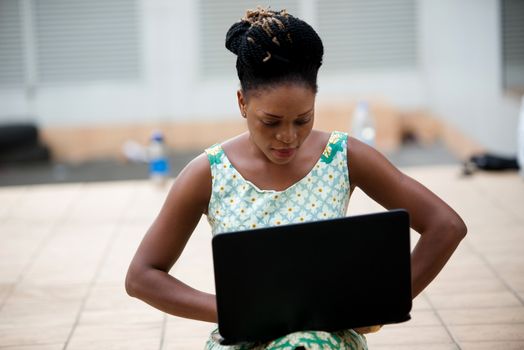 Close up of woman working on laptop sitting outdoors