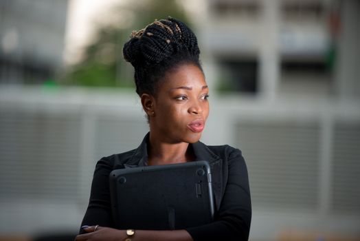 businesswoman standing outside and pensive holding a laptop against her chest