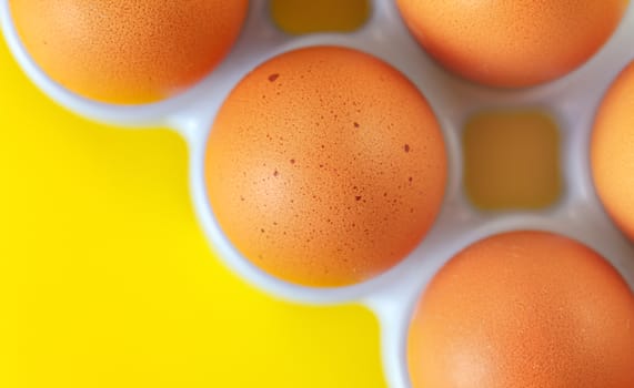 Beige coloured eggs on yellow board, closeup detail, space for text left down corner.