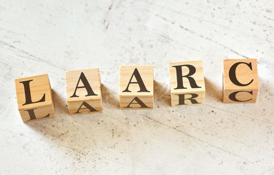 Five wooden cubes with acronym LAARC means Listen, Acknowledge, Assess, Respond, Confirm one of objection handling techniques, on white stone like board, view from above.