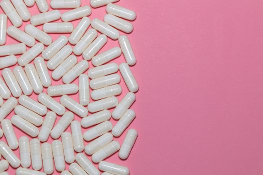 Top view of white pills on pink background with copy space. Healthcare, medical and pharmaceutical concept.