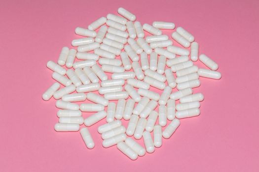High angle shot of white pills on pink background. Healthcare, medical and pharmaceutical concept.