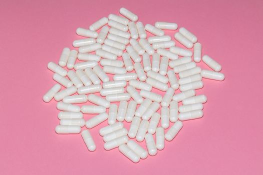 High angle shot of white pills on pink background. Healthcare, medical and pharmaceutical concept.