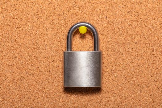 Closed padlock hanging on an empty corkwood notice board in business office. Safety and security reminder, business closure concepts. Close up shot.