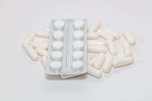 High angle shot of various white pills on white background. Some of them are out of focus. Pharmaceutical business and medicine sale concepts.