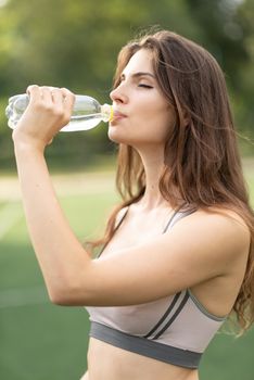 Young girl athlete drinks water during a break