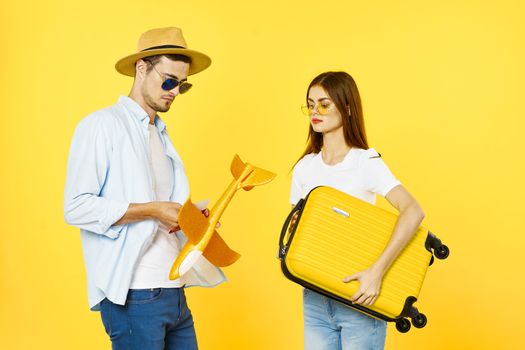 Man and woman tourists airplane travel passenger baggage airport yellow background
