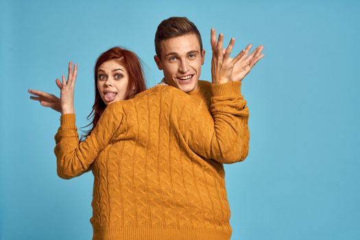 couple in yellow sweater posing against blue background cropped view. High quality photo