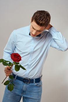 Handsome man with red rose blue shirt bow tie light background cropped view. High quality photo