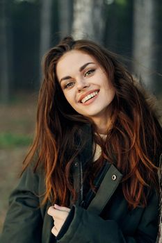 smiling woman in jacket outdoors in the forest travel. High quality photo