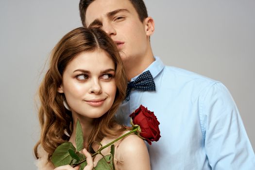 Young couple romance hug relationship dating red rose light studio background. High quality photo