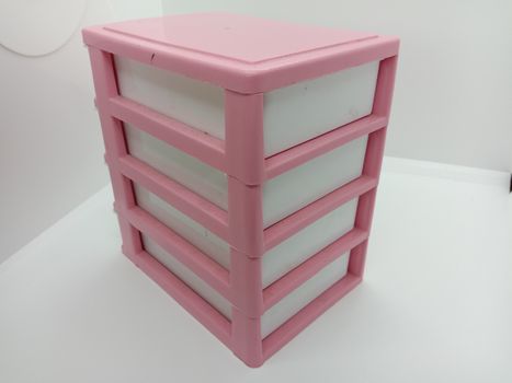 pink and white colored plastic toy wardrobe on white background