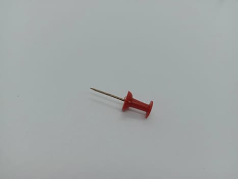 red colored push pin on white background