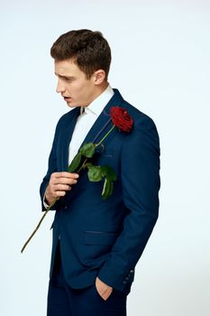 A man in a suit with a rose in his hands a gift date light background. High quality photo