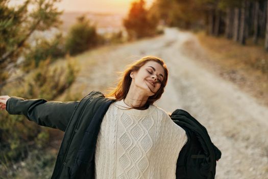 Woman throws up her hands outdoors closed eyes Freedom fresh air travel. High quality photo