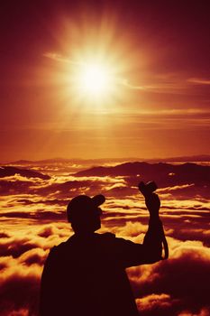 tourist man hold camara with sunrise and sea of fog view on phu chi fa mountain area and national forest park in chiang rai, Thailand.