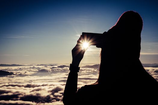 tourist girl taking photo sunrise and sea of fog view on phu chi fa mountain area and national forest park in chiang rai, Thailand.