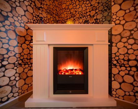A burning fireplace in the room. White beautiful fireplace.