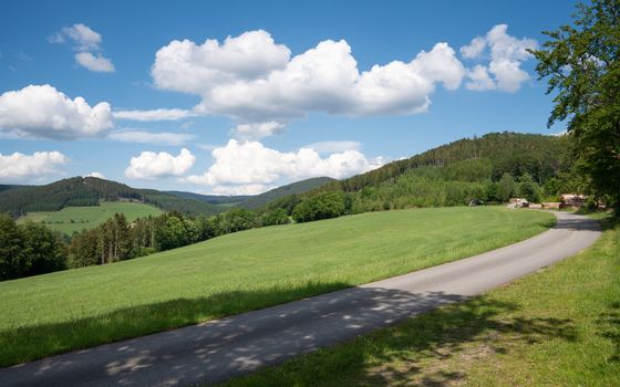 Panoramic image of the Sauerland region close to Winterberg with a hiking trail through a green meadow, Germany