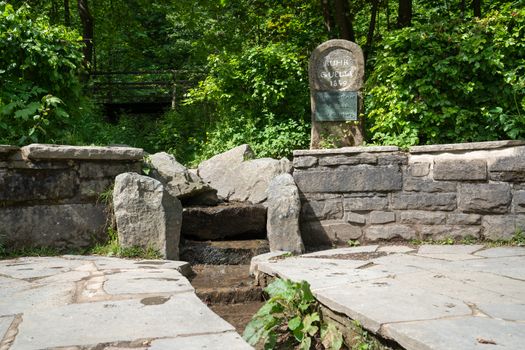 Spring of the river Ruhr with memorial stone and surrounded by trees, Winterberg, Sauerland, Germany
