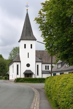 View along the central street of the Sauerland village Westfeld with parish church, old buildings and tree, Schmallenberg, Germany