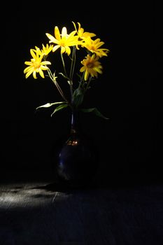 Nice yellow wildflowers in glass vase against black background