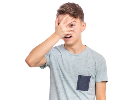 Surprised handsome teen boy covering his eyes with hand, isolated on white background