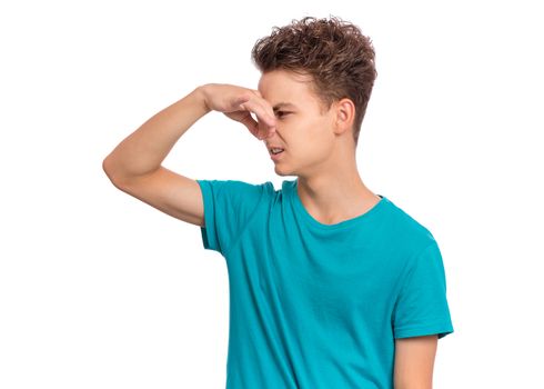 Handsome teen boy closes his nose from an unpleasant smell, isolated on white background