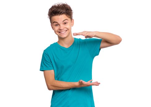 Handsome teen boy shows something in his hands and looking at camera, isolated on white background