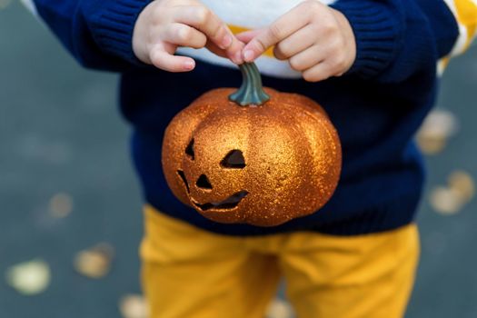 Children's hands holding a toy pumpkin lantern for the holiday halloween