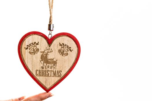 Hand holding heart shaped Christmas decoration isolated on white.